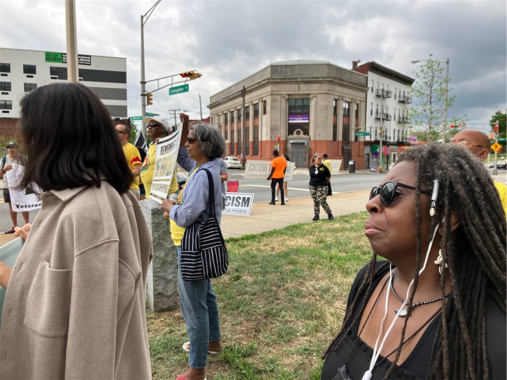 Activists in Newark on grassy area, seen from the side of the action, as though the photographer is in the group.