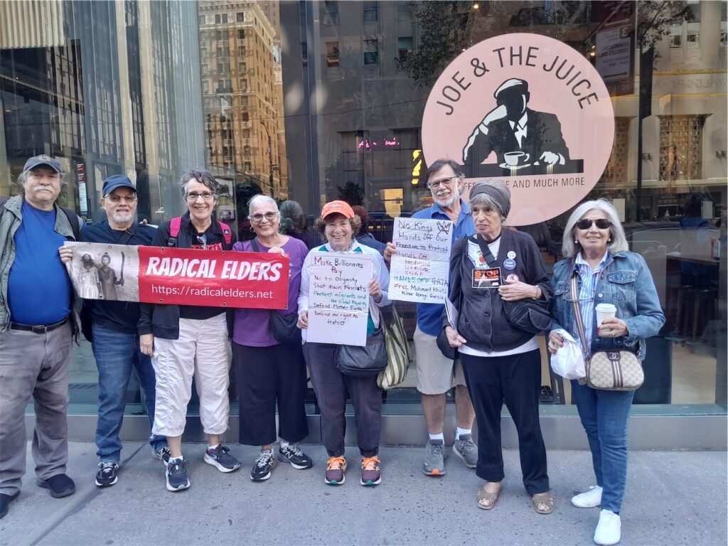 Radical Elders hold RE banner and handmade signs outside Joe & the Juice before the march